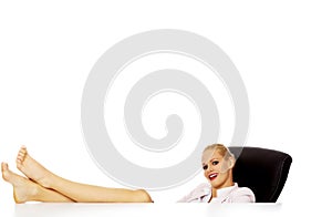 Happy business woman holding legs on the desk