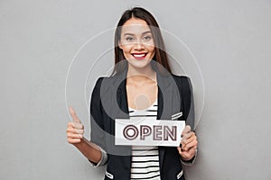 Happy business woman holding nameplate open and showing thumb up