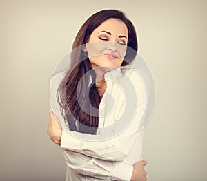 Happy business woman hugging herself with natural emotional enjoying face with closed eyes on color background. Love concept of