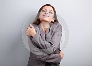 Happy business woman hugging herself with natural emotional enjoying face. Love concept of yourself