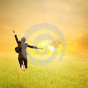 Happy business woman jumping in green rice field and sunset