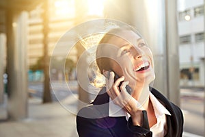 Happy business woman laughing on mobile phone outside