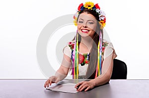 Happy business woman with note and pen by a desk In the Ukrainian national costume