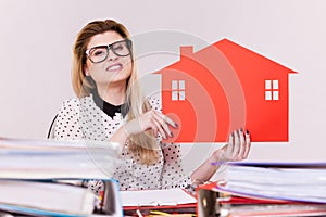 Happy business woman in office holding house