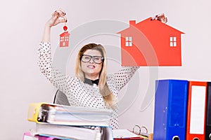 Happy business woman in office holding house