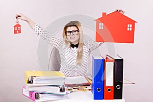 Happy business woman in office holding house