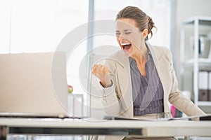 Happy business woman in office rejoicing success