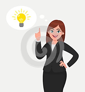 Happy business woman pointing hand up and bright light bulb appearing in the thought bubble.