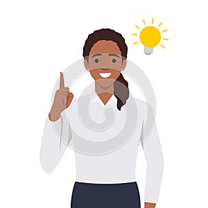 Happy business woman pointing hand up and bright light bulb appearing in the thought bubble. Idea and innovation concept