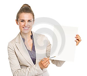 Happy business woman pointing with pen on blank paper sheet