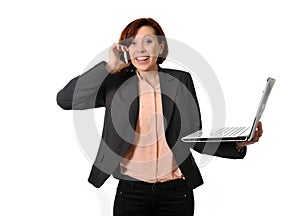 Happy business woman with red hair talking on the mobile cell phone holding laptop