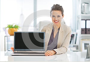 Happy business woman showing laptop blank screen