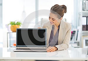 Happy business woman showing laptop blank screen