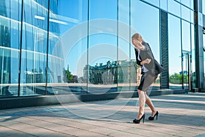 Happy business woman showing thumbs up while standing outdoors against office