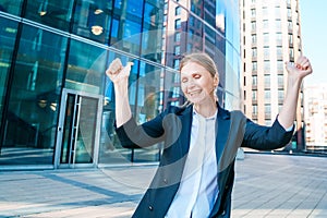 Happy business woman showing thumbs up while standing outdoors against office