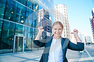 Happy business woman showing thumbs up while standing outdoors against office