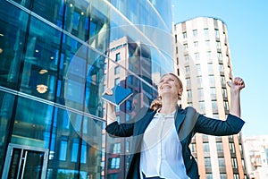 Happy business woman showing thumbs up while standing outdoors against office