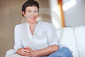 Happy business woman sitting on sofa. Portrait of mature business woman smiling while sitting on sofa.