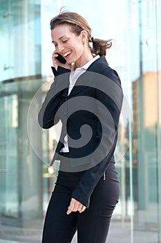Happy business woman talking on cell phone outside