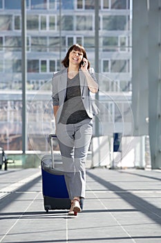 Happy business woman talking on mobile phone at airport