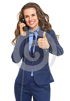 Happy business woman talking phone and showing thumbs up