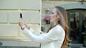 Happy business woman talking video call by mobile phone outdoors