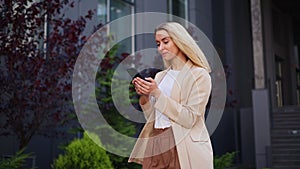Happy business woman typing on mobile phone walking with smartphone.