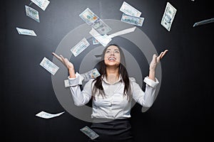 Happy business woman under a money rain made of dollars isolated on black