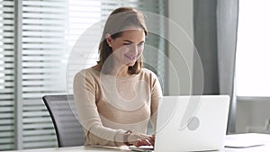 Happy business woman using computer communicating online sitting at desk