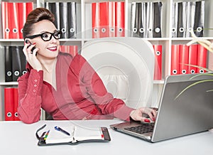 Happy business woman using mobile phone and working with laptop