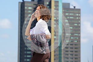 Happy business woman walking and talking on cell phone