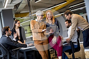 Happy business women working together online on a digital tablet at the office