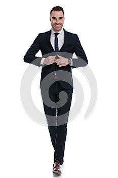 Happy businessman adjusting jacket and smiling while walking