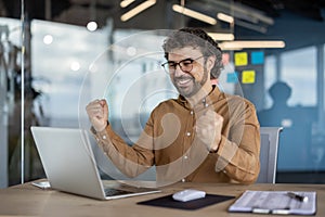 Happy businessman celebrating success at office desk