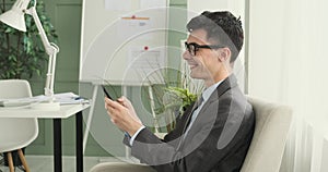 Happy Businessman Chatting on Phone While Seated in Chair