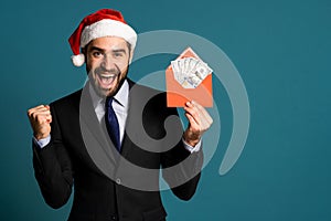 Happy businessman in corporate suit with tie holding dollars money in envelope