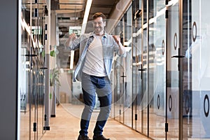 Happy businessman dancing in office hallway, celebrating success