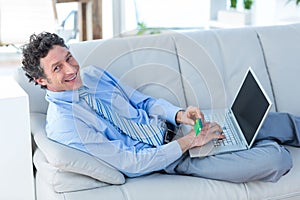 Happy businessman doing online shopping on couch