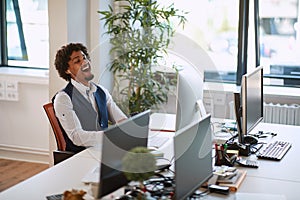 Happy businessman with earphones looking at the screen. Man sitting at a desk smiling at work