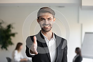 Happy businessman extending arm at camera for hand shake