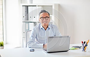 Happy businessman in eyeglasses with laptop office