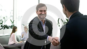 Happy businessman in eyeglasses shaking hands with partner.