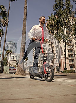 Happy businessman have fun riding e-scooter along city street, e-scooting