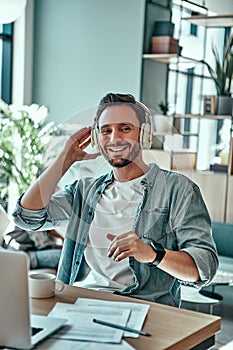 Happy businessman in headphones listening music while sitting in cafe