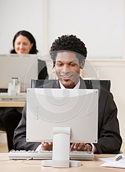 Happy businessman in headset working on computer