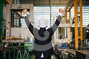 Happy businessman with helmet in factory