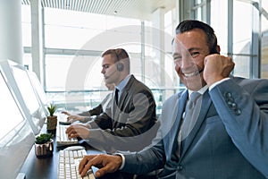 Happy Businessman with his colleagues working on computer at desk in office