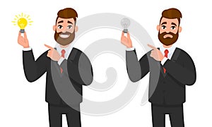 Happy businessman holding bright bulb and pointing to it. Unhappy businessman holding bulb and pointing.