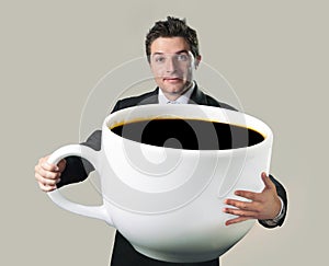 Happy businessman holding funny huge oversized cup of black cof photo