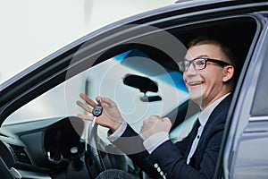 Happy businessman holding keys to his new car